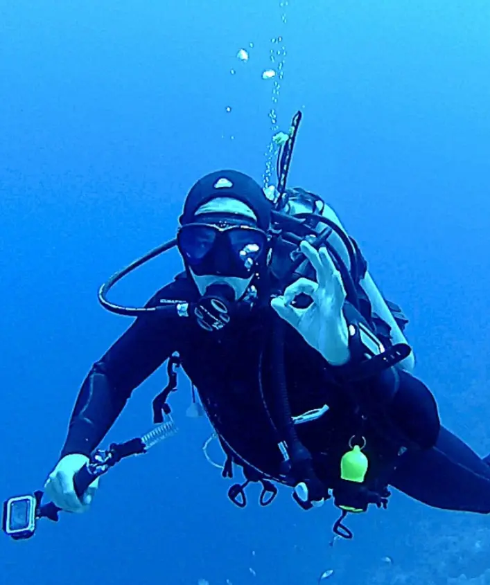 A scuba diver is in the water with his gear.