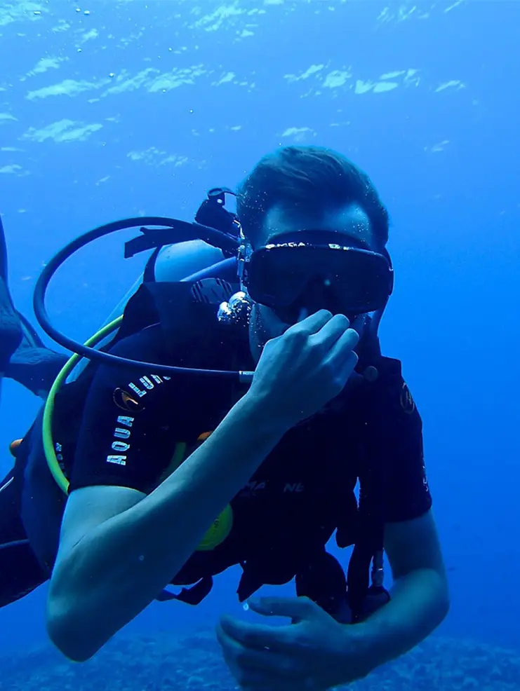 A man in black shirt holding rope underwater.