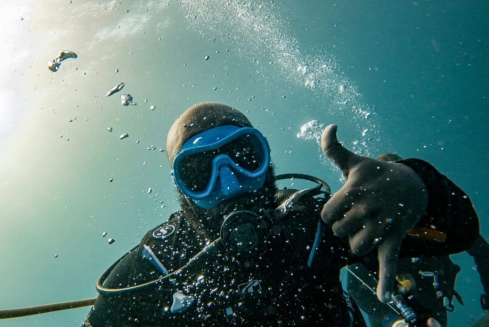 A man in scuba gear is giving the thumbs up.